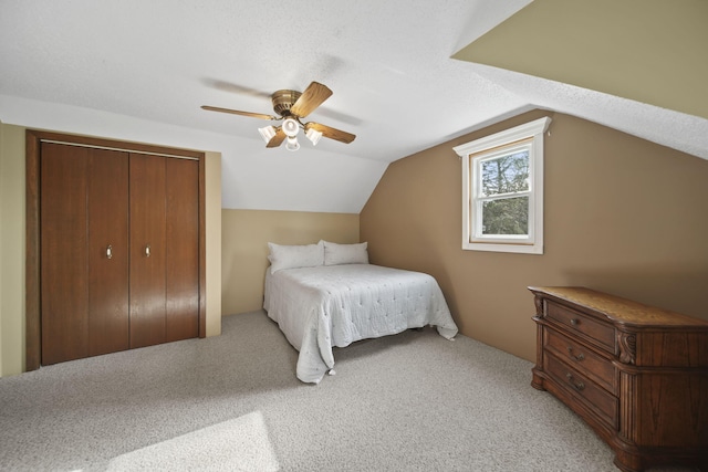 bedroom featuring a ceiling fan, light colored carpet, vaulted ceiling, and a closet
