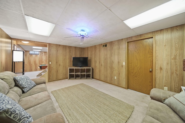 carpeted living room with wood walls, a drop ceiling, and visible vents