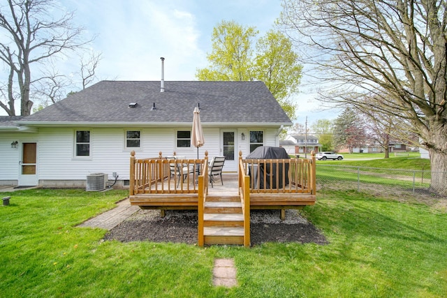 rear view of property featuring a shingled roof, fence, a yard, and a wooden deck