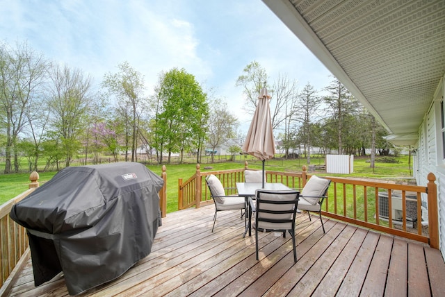 wooden deck with a lawn, outdoor dining area, and grilling area