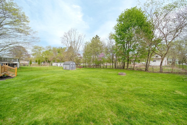 view of yard featuring a storage unit, a fenced backyard, an outdoor fire pit, and an outbuilding