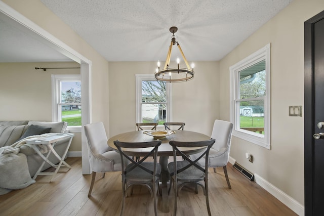 dining area with an inviting chandelier, plenty of natural light, and wood finished floors