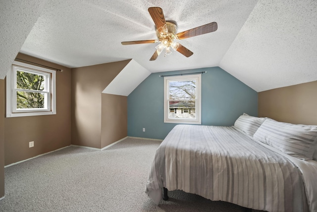 bedroom featuring carpet floors, multiple windows, a textured ceiling, and lofted ceiling