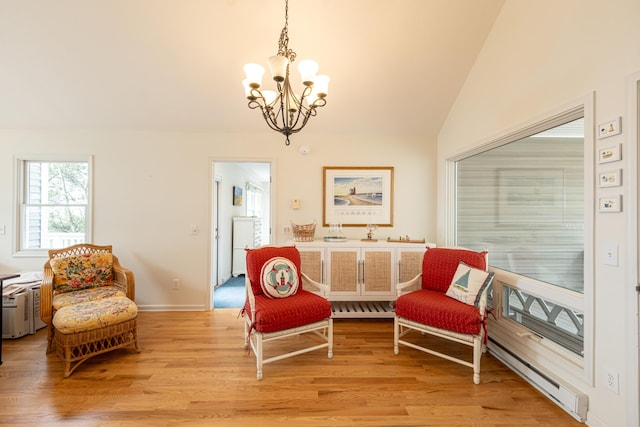 sitting room featuring an inviting chandelier, light wood-style flooring, baseboards, lofted ceiling, and a baseboard radiator