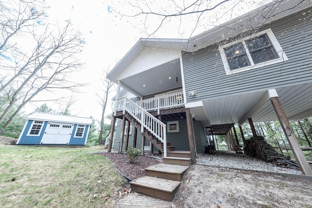 back of house featuring a storage shed, a deck, a carport, an outdoor structure, and stairs