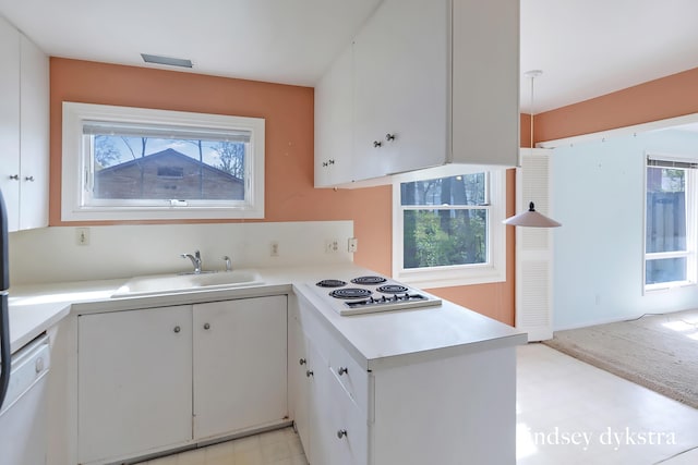 kitchen featuring a sink, light countertops, white electric stovetop, and a wealth of natural light