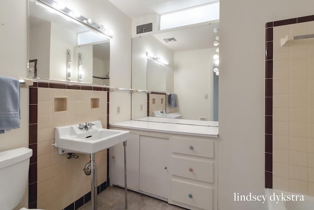 bathroom featuring toilet, visible vents, tile walls, and tile patterned flooring