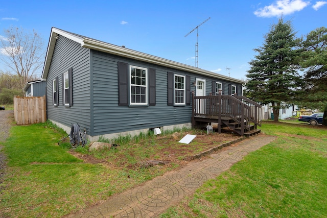 view of front of home featuring a deck, fence, and a front lawn