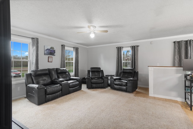 living area with a ceiling fan, a textured ceiling, light colored carpet, crown molding, and baseboards