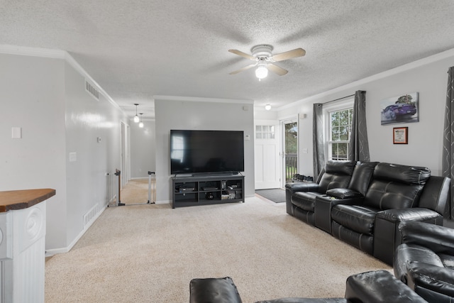 carpeted living area with visible vents, a ceiling fan, a textured ceiling, and crown molding