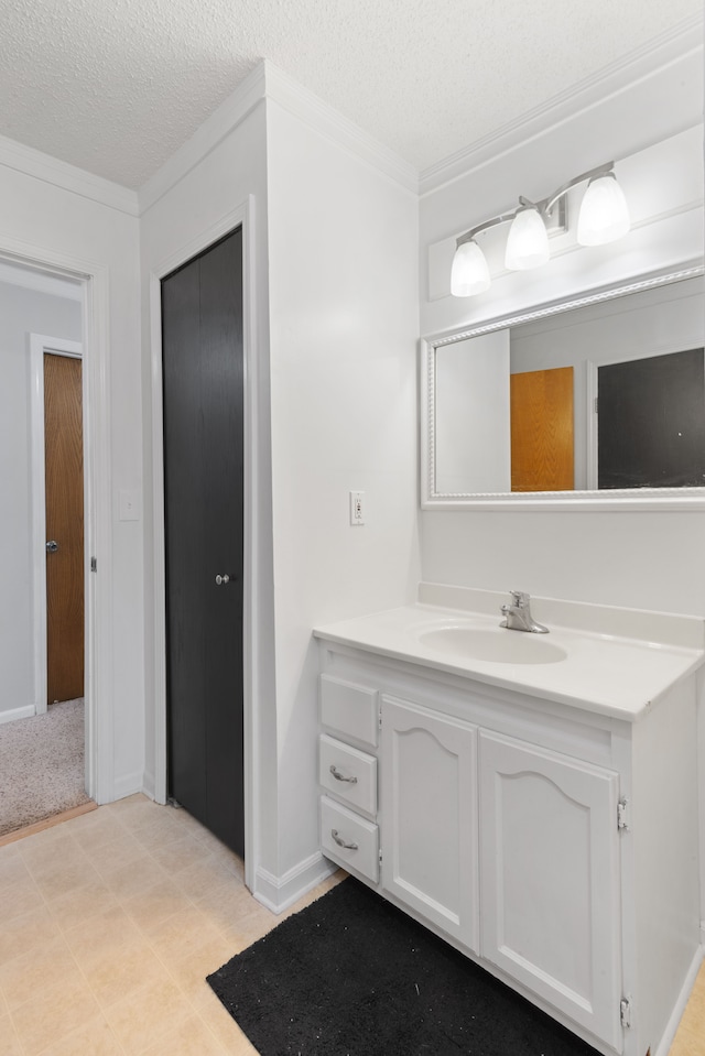 bathroom featuring vanity, ornamental molding, a textured ceiling, and baseboards