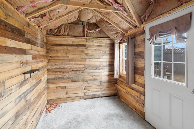spare room featuring wooden walls, vaulted ceiling, and carpet floors