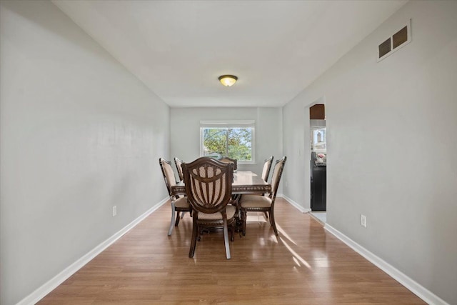 dining area featuring baseboards, light wood-style flooring, and visible vents