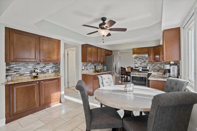 dining space featuring light tile patterned floors, a raised ceiling, and ceiling fan