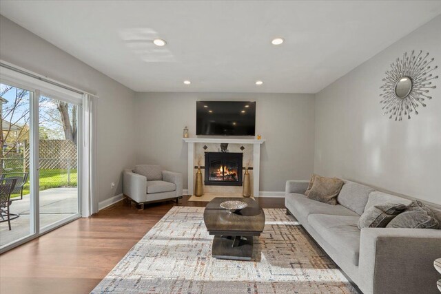 living room with recessed lighting, a fireplace with flush hearth, baseboards, and wood finished floors