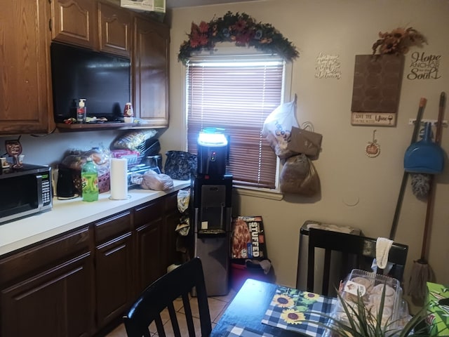 kitchen featuring light countertops, light tile patterned flooring, and stainless steel microwave