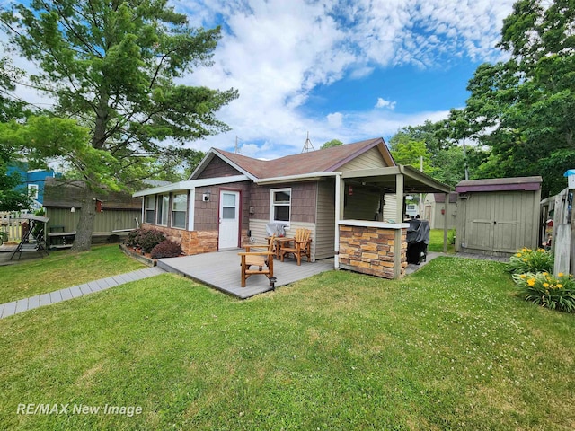 back of property featuring an outdoor structure, stone siding, a deck, a shed, and a lawn