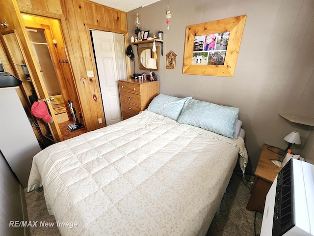 carpeted bedroom featuring wooden walls and a closet