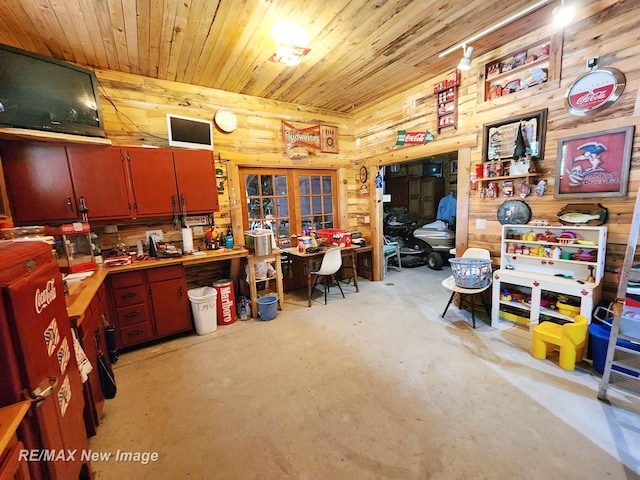 interior space with wood ceiling, a workshop area, french doors, concrete flooring, and wooden walls