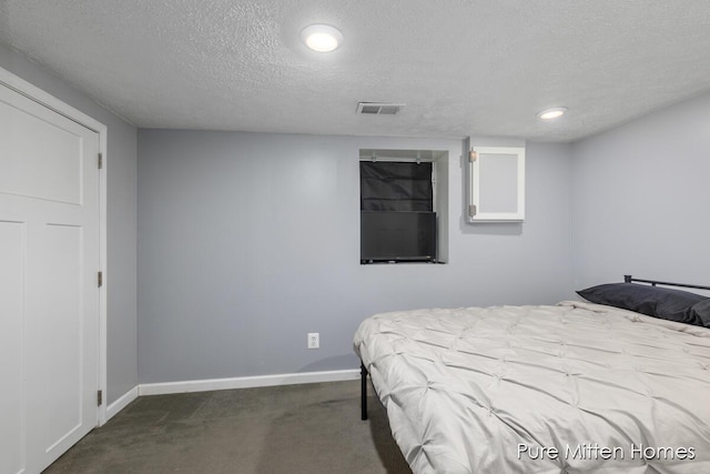 bedroom featuring baseboards, dark colored carpet, a textured ceiling, and visible vents