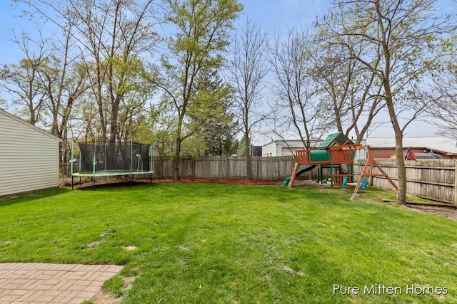 view of yard with a playground, a fenced backyard, and a trampoline