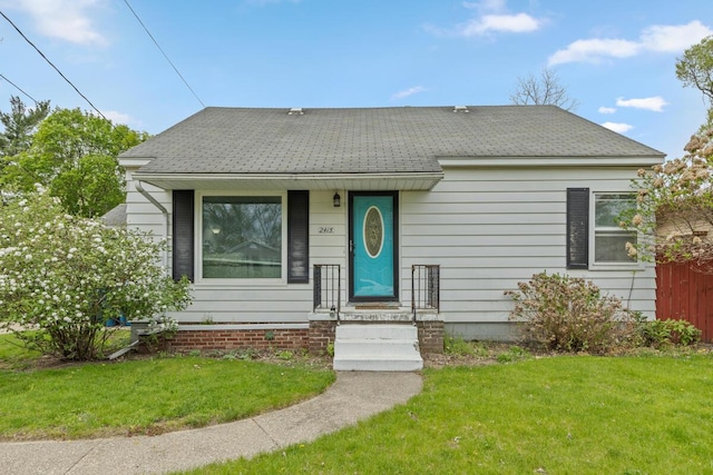 view of front of property with a shingled roof and a front yard