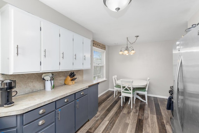kitchen with white cabinets, light countertops, freestanding refrigerator, backsplash, and dark wood-style floors