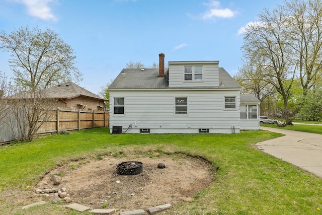 back of property with fence, a chimney, central air condition unit, a lawn, and a fire pit