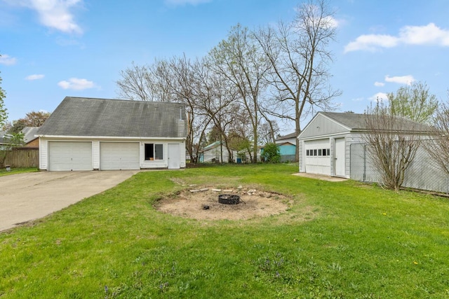 view of yard with a garage, an outbuilding, and a fire pit
