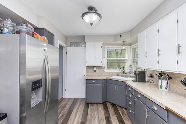 kitchen with backsplash, a sink, white cabinets, stainless steel fridge, and dark wood-type flooring