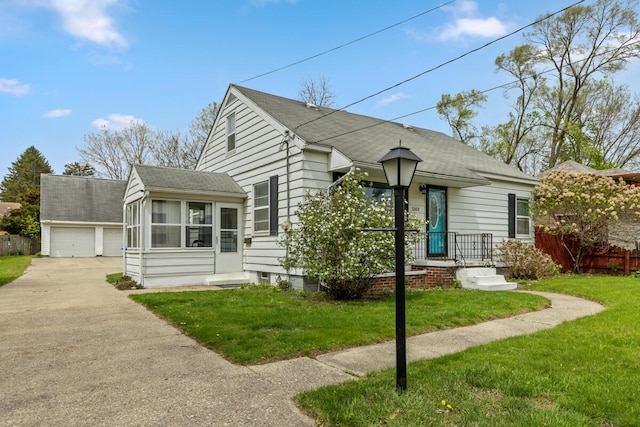 bungalow with roof with shingles, an outbuilding, a sunroom, a detached garage, and a front lawn