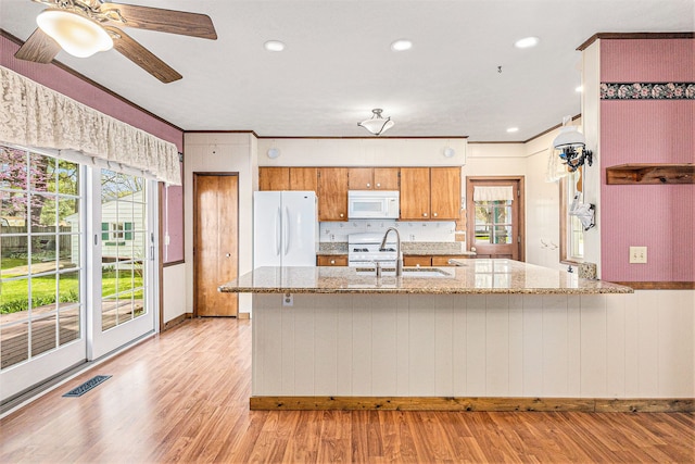 310 E Unadilla St, Pinckney, MI 48169 - kitchen featuring a sink, light wood finished floors, white appliances, a peninsula, and visible vents