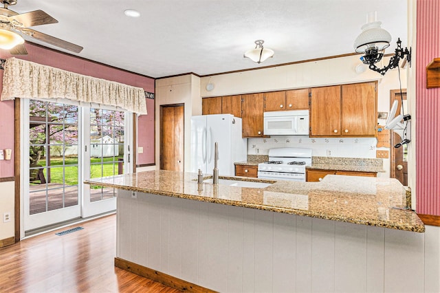310 E Unadilla St, Pinckney, MI 48169 - kitchen with a sink, light wood finished floors, white appliances, brown cabinetry, and baseboards