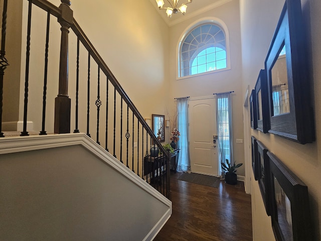 entrance foyer featuring wood finished floors, a high ceiling, an inviting chandelier, ornamental molding, and stairs