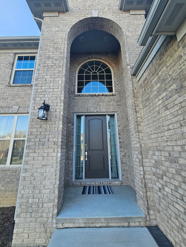 view of exterior entry featuring brick siding