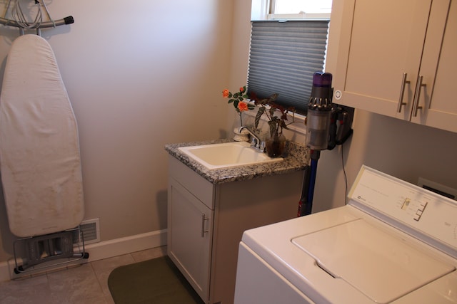 laundry area with cabinet space, light tile patterned flooring, a sink, baseboards, and washer / dryer