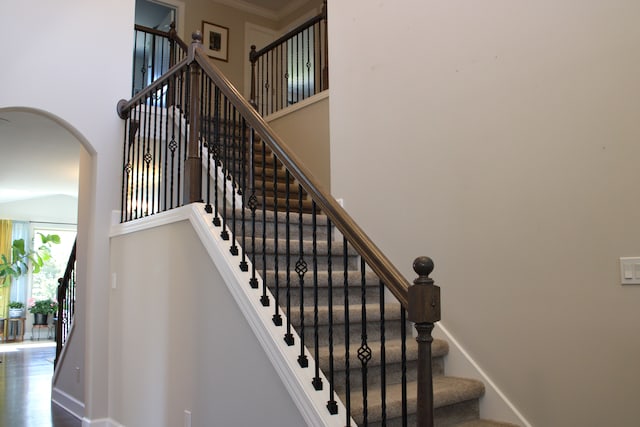 stairway with arched walkways and baseboards