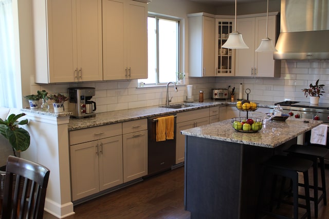 kitchen with decorative backsplash, a kitchen bar, a sink, wall chimney exhaust hood, and dark wood-type flooring