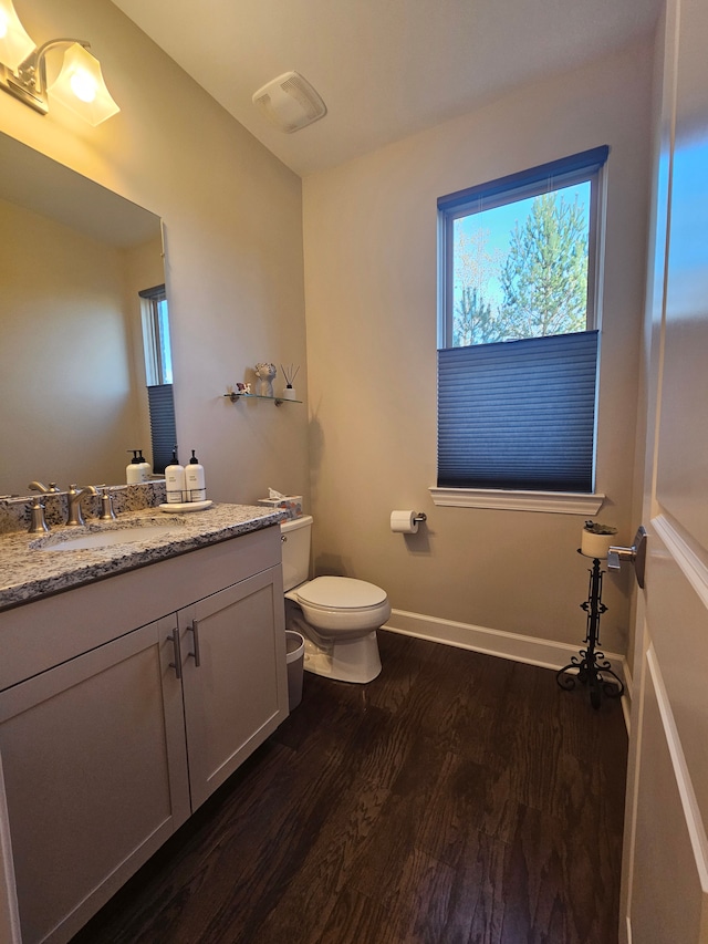bathroom with visible vents, vanity, wood finished floors, toilet, and baseboards