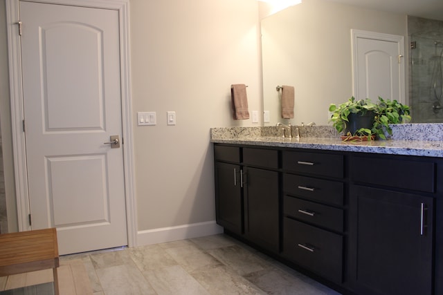 bathroom featuring baseboards, a tile shower, and vanity