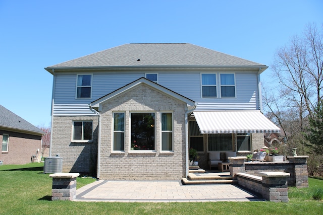back of property featuring a lawn, central AC unit, a patio area, and brick siding