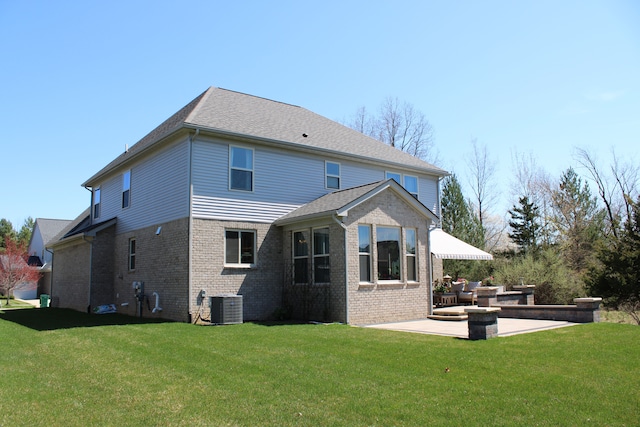 back of house featuring a lawn, a patio, central AC, and brick siding