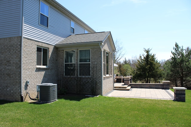 exterior space with a yard, brick siding, central AC, and a patio area