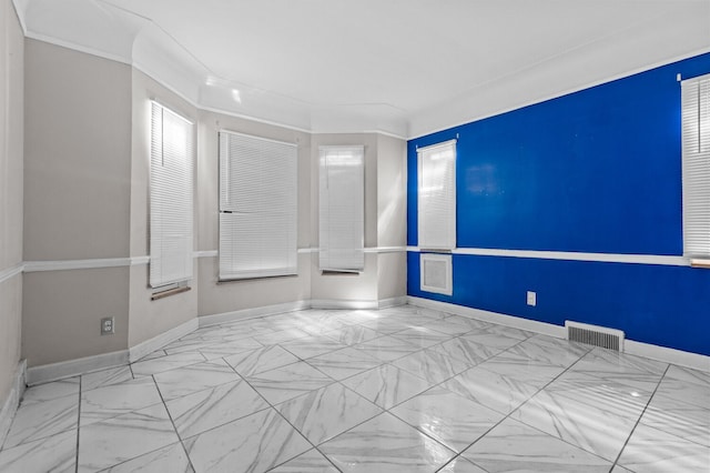 spare room with baseboards, ornamental molding, marble finish floor, and visible vents