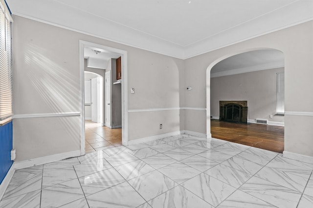 empty room with visible vents, a fireplace with flush hearth, arched walkways, marble finish floor, and ornamental molding