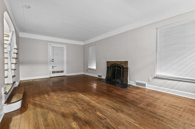 unfurnished living room with a fireplace with flush hearth, baseboards, wood finished floors, and visible vents