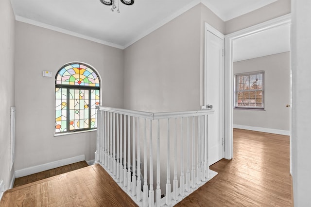 corridor featuring baseboards, an upstairs landing, ornamental molding, and wood finished floors