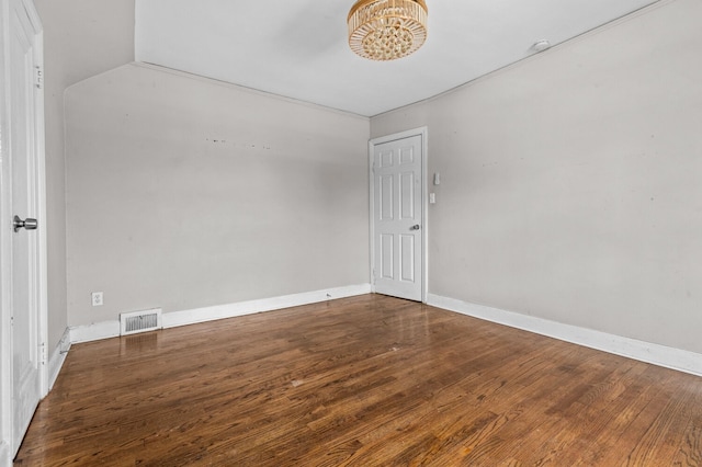 unfurnished room with visible vents, baseboards, wood finished floors, and a notable chandelier