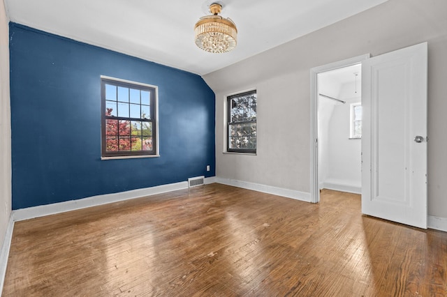 spare room featuring visible vents, baseboards, wood finished floors, and a notable chandelier