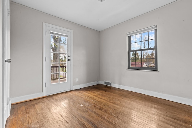 empty room with visible vents, baseboards, a healthy amount of sunlight, and hardwood / wood-style flooring